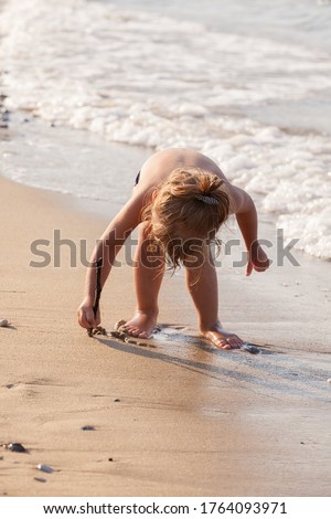 a little girl  playing in the sand in the shallows, note shallow depth of field