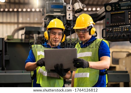 Colleagues in industrial engineering or management of work done Holding a male mechanic. Technicians or engineers are inspecting machine operations using a laptop computer. Royalty-Free Stock Photo #1764126812
