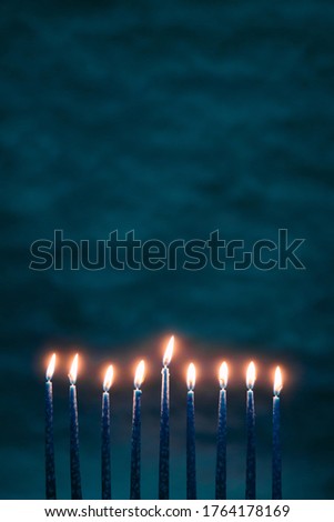 Burning blue candles on a Jewish menorah at Hanukkah  on a dark blue background