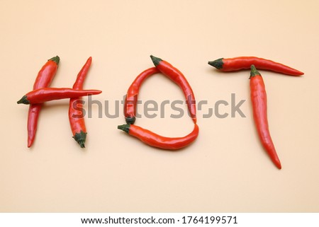Red chile peppers doing the word hot on a salmon background.