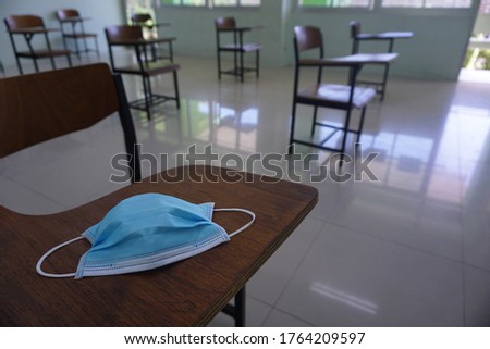 Medical face blue mask on the wood lecture chairs place distancing in the empty classroom. Concept during the Coronavirus disease COVID-19 outbreak in the 2020s. Back to school concept. Royalty-Free Stock Photo #1764209597