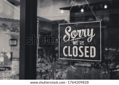 " Sorry we're closed " sign in black and white, on shop glass door.monotone.