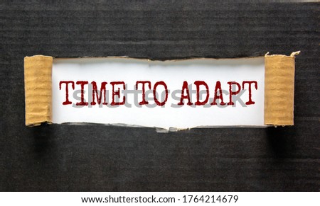 The words 'time to adapt' appearing behind torn black paper. Beautiful background. Business concept.