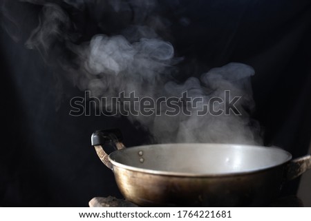 Blurred picture of white smoke form stainless steel pan on stove with black background in countryside kitchen.  Royalty-Free Stock Photo #1764221681