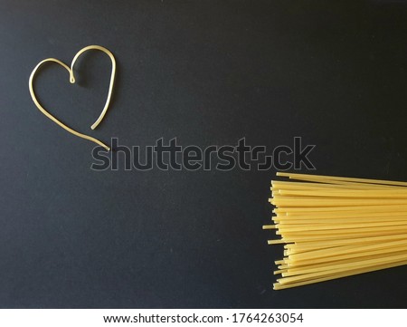 Colorful template for cooking topics. A pile of raw spaghetti on one side and a heart shape drawn with a noodle. Background image for presentations, powerpoint, seminars. Useful for recipe concepts.