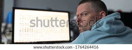 Portrait of serious man using desktop computer. Focused male person turning around looking at camera with surprise and calmness. Businessman spending time at home