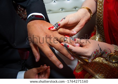 A bride is wearing a ring on the groom's finger. Indian Wedding.
