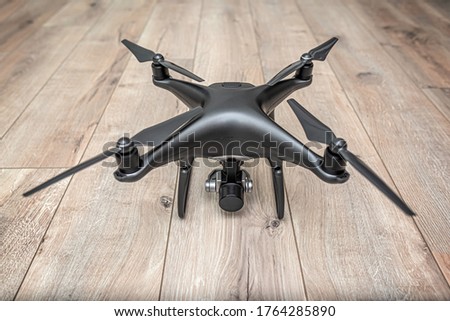 Dark drone on a wooden background. Unmanned aerial vehicle on the background of the boards.