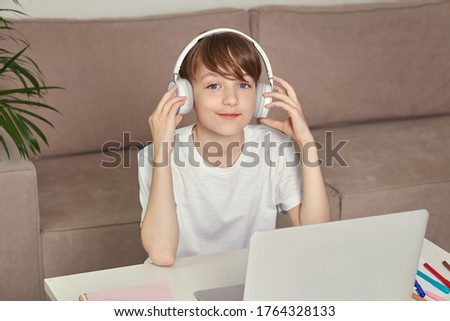 Handsome smiling guy is studying at home online with headphones on his head