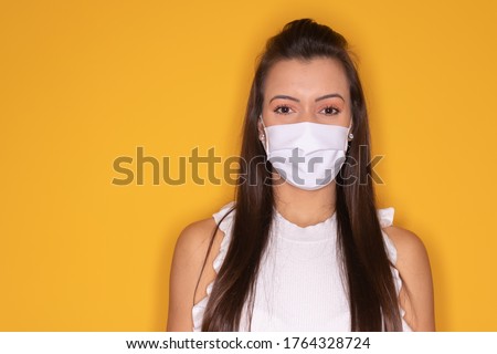 Woman with protective mask against covid 19 in yellow background Royalty-Free Stock Photo #1764328724