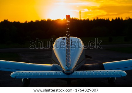 Quadruple aircraft parked at a private airfield. Rear view of a plane with a propeller on a sunset background. Royalty-Free Stock Photo #1764329807