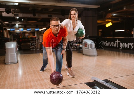 A beautiful loving caucasian couple throwing balls on the bowling alley. Boyfriend and girlfriend at the bowling club