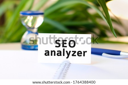 Seo analyzer seo business concept text on a white notebook and hourglass, blue pen, green flowers