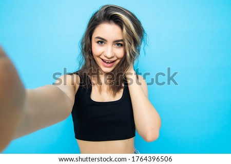 Young woman taking a selfie on blue ground