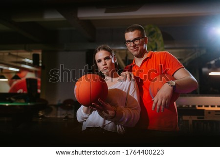 A beautiful caucasian woman and a man are playing basketball in a playroom. Love and recreation
