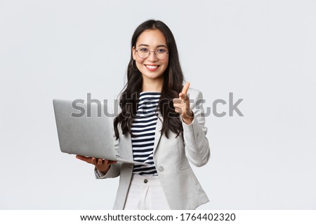 Business, finance and employment, female successful entrepreneurs concept. Smiling pleased businesswoman praise coworker who made good point, pointing finger camera satisfied, hold laptop