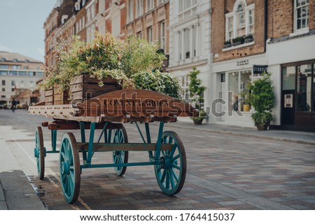 'Covent Garden" area name sign on a wooden cart with flowers on a street in Covent Garden, London, UK, on a bright summer day. Selective focus.
