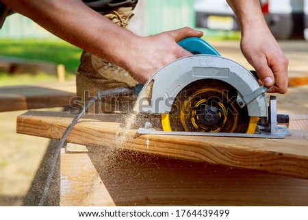 Builder saws a board with a circular saw in the cutting a wooden plank Royalty-Free Stock Photo #1764439499