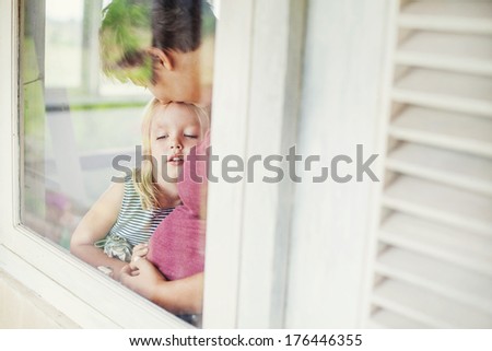 Mother and daughter looking through the window