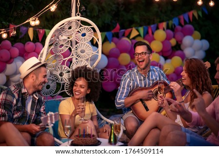 Party, holidays, celebration and people concept.Smiling friends celebrate birthday at night party.