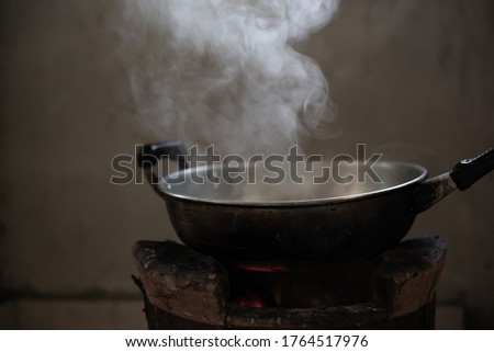 Blurred picture of white smoke from boiling water in stainless steel pot on stove in countryside kitchen.