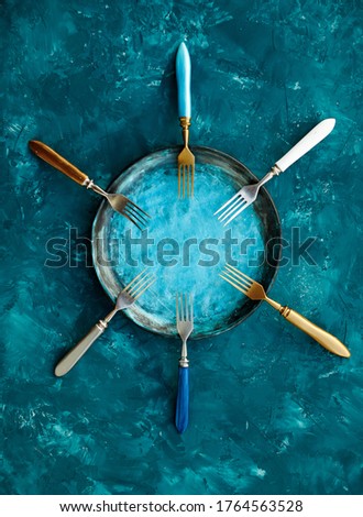 Colored set of kitchen plate with forks on a turquoise blue background.