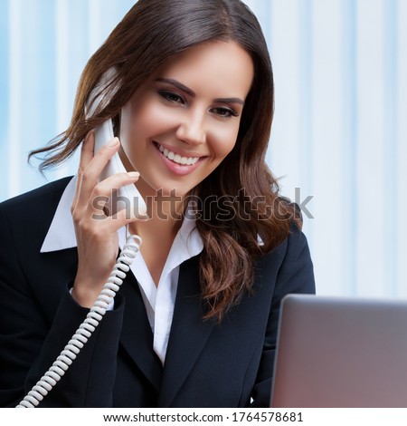 Portrait image of businesswomen or customer support female phone operator or sales agent in confident suit, with phone and laptop at office. Assistance service call center, zoom conference consulting.