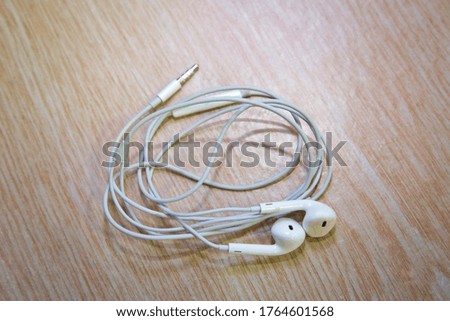 Earbud or earphone top view on wooden background . White earphones from the phone