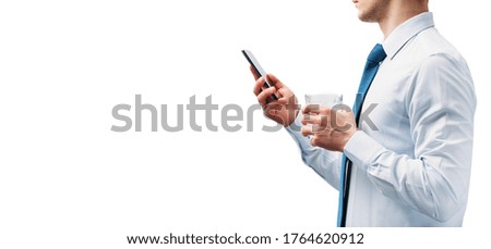 A guy in a white shirt and blue tie on a white background. A man looks at the phone screen and holds a glass with a cocktail. A place for an inscription. An object from the  right.