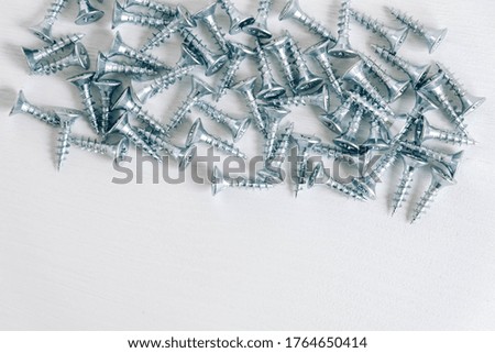 Metal tapping screws for wood on white wooden background. Construction equipment concept. Top view. Copy, empty space for text