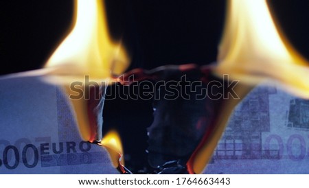 Burning euros, global financial crisis and inflation, concept. Money banknote on a black background, burning and Smoking, natural shooting