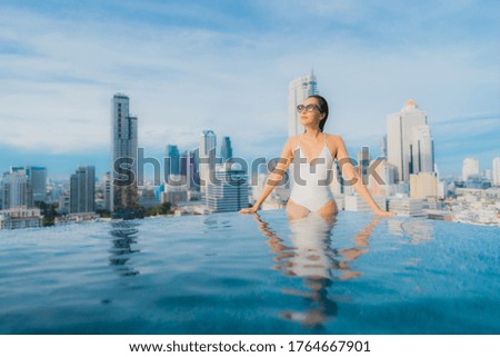 Portrait beautiful young asian woman relax happy smile leisure around outdoor swimming pool with cityscape
