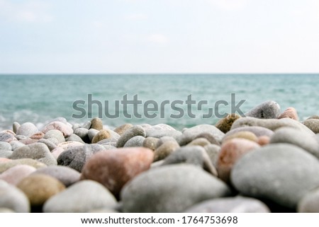 Seascape with colourful stones in the foreground. Calm and cozy background with blue sky and sea with pebble