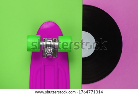 Retro style. Plastic mini cruiser board and vinyl record on colored background. Summer fun. Youth minimalistic concept. 80s. Top view