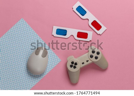 Retro entertainment. Old-fashioned pc mouse, gamepad, anaglyph stereo glasses on blue pink background. Top view. Flat lay