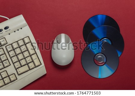 Old-fashioned retro keyboardб CD's and pc mouse on red background. Top view