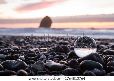 coastal sunset inverted on a clear glass sphere using a wide angle lens to capture a slightly blurred scene in the background