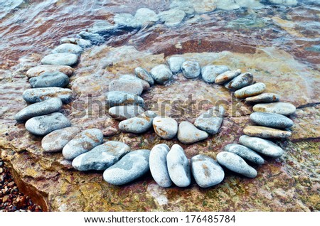 Spiral of white pebbles on the sea boulder