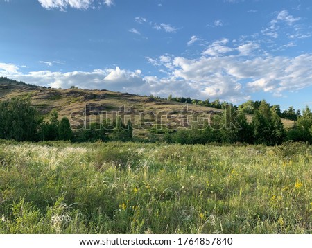 Panoramic view. Beautiful summer landscape. Mountains, blue sky and green fields, forestA group of clouds in the sky