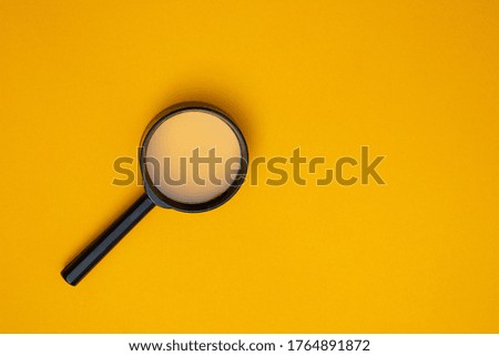 Magnifying glass on orange background. Copy space