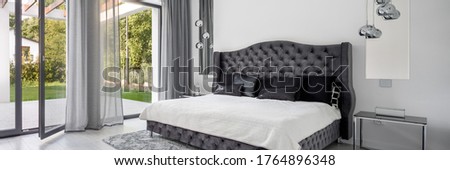 Panorama of elegant and glamorous bedroom with big quilted gray bed