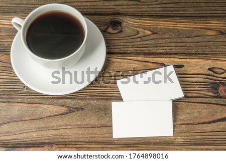 White clean business cards and a cup of coffee on a wooden table. Business concept idea, advertising, negotiations, coffee break, Promotion