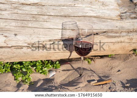 a background of dry wood a glass of red wine stands on the sand against