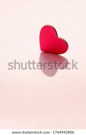 Pink heart stands on a pink background. Vertical frame.