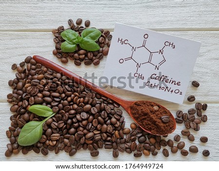 Structural chemical formula of caffeine molecule with roasted coffee beans and wooden spoon filled with coffee powder. Caffeine is a central nervous system stimulant, psychoactive drug molecule. Royalty-Free Stock Photo #1764949724
