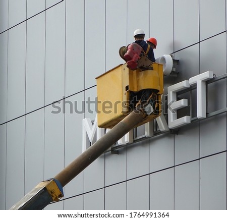   Repair work at a height to correct a damaged sign on a store                             