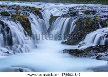 Beautiful and powerful of white streaming at Bruarfoss waterfall and black lava rock around waterfall in evening,Summer,Iceland.