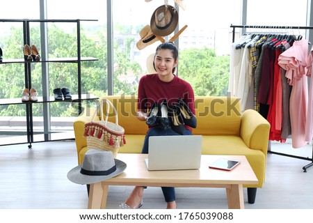 Beautiful Asian woman blogger recording on video Dslr Camera for selling shoes in online shopping website on yellow sofa. Marketing in social media concept.
