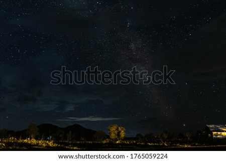 Night landscape with colorful Milky Way and yellow light at mountains. 