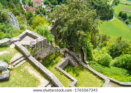Scenic view from the top of the castle ruins of Hohengundelfingen, Germany  down to a fresh green river valley. The ruins show stone walls with stairs, surrounded by deciduous trees and rough rocks.